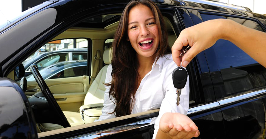 fiatal hölgy boldogan veszi át az új autójának kulcsait